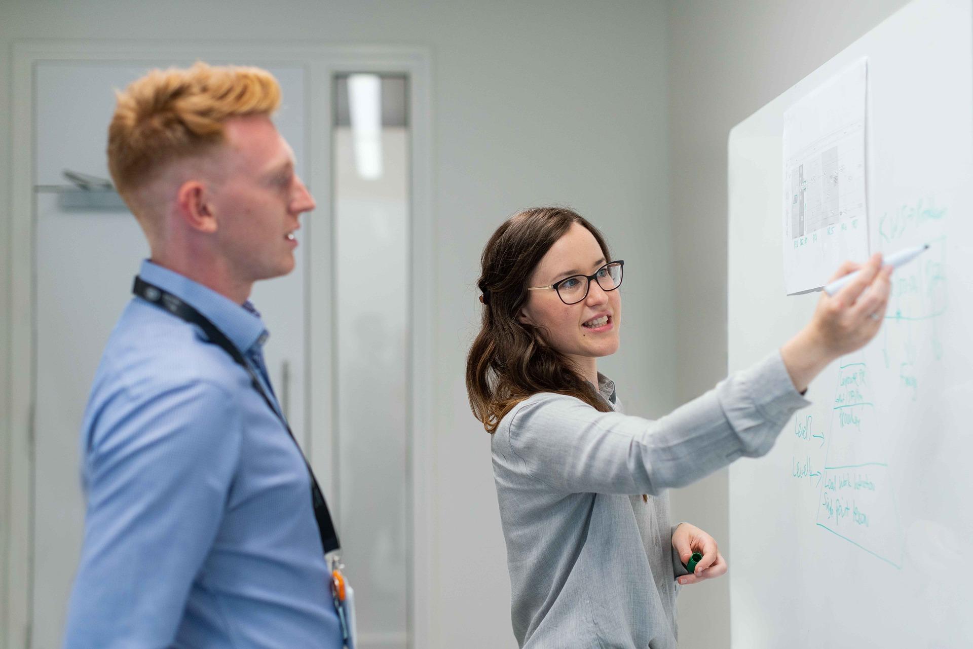 Two people working through a plan together at a whiteboard